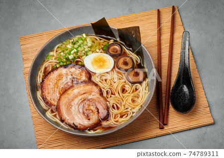A Shoyu Ramen in gray bowl on concrete table top. Japanese cuisine meat noodle soup with chashu pork A Shoyu Ramen in gray bowl on concrete table top. Japanese cuisine meat noodle soup with chashu pork 74789311