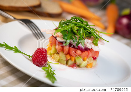 Tartare of fresh diced vegetables and salads in a white plate decorated with a raspberry Tartare of fresh diced vegetables and salads in a white plate decorated with a raspberry 74789925