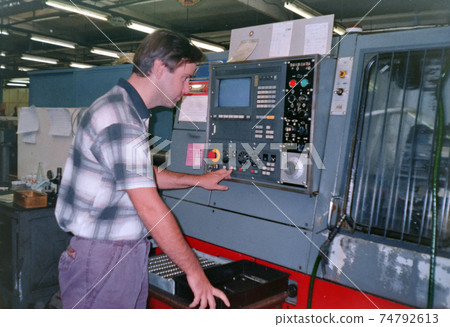 A man operates a numerical control machine in a factory, archive photo, 90s. Czech republic. A man operates a numerical control machine in a factory, archive photo, 90s. Czech republic. 74792613