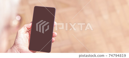Cell phone in old hands over shoulder. Cell phone in old hands over shoulder. 74794819