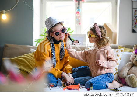 Sisters indoors at home, playing on bed. Lockdown and dressing up concept. 74794887