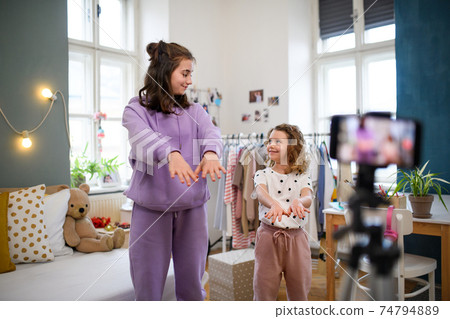 Sisters indoors at home, making video with smartphone. Lockdown concept. Sisters indoors at home, making video with smartphone. Lockdown concept. 74794889