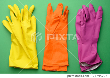 three pairs of rubber gloves for cleaning on a green background, top view 74795723