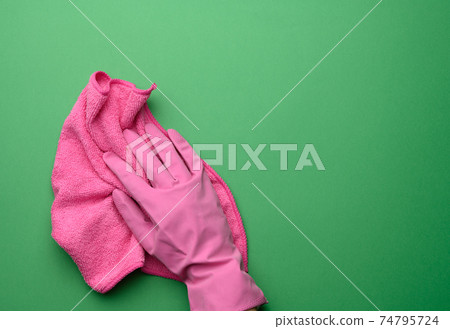 female hand in a pink rubber glove holds a pink cleaning rag on a purple background, close up female hand in a pink rubber glove holds a pink cleaning rag on a purple background, close up 74795724