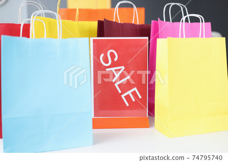 Lot of multicolored packages standing near sale plate closeup Lot of multicolored packages standing near sale plate closeup 74795740