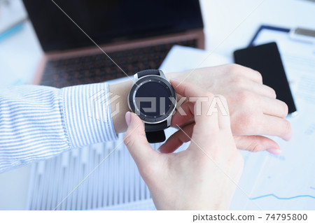 Woman looking at smart watch at workplace closeup Woman looking at smart watch at workplace closeup 74795800