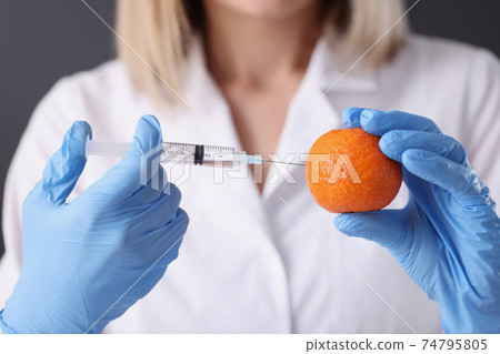Doctor beautician in gloves making injection into orange closeup 74795805