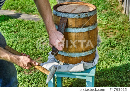 Oak Barrel. Opening the barrel with a chisel and hammer Oak Barrel. Opening the barrel with a chisel and hammer 74795915