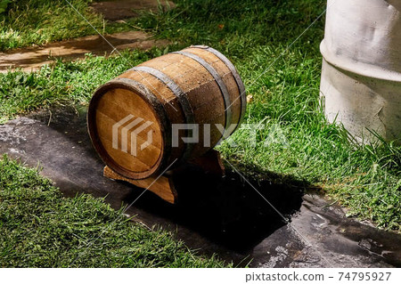 Oak barrel for storage wine lies on special support in yard 74795927