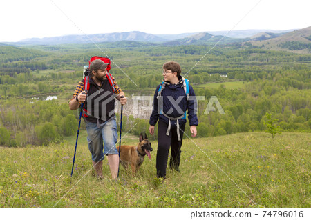 Father, son and their dog on a journey in mountains. 74796016