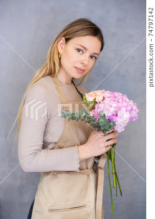 Young caucasian female florist collects a romantic bouquet of roses. 74797142