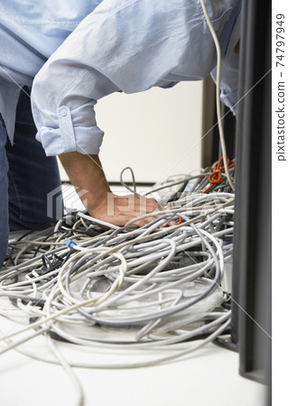 Man Working On Tangled Computer Wires 74797949