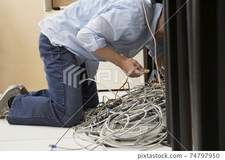 Man Working On Tangled Computer Wires 74797950