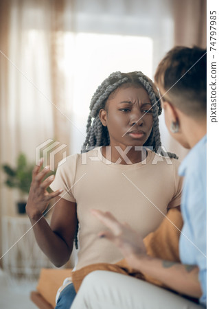 Dark-skinned girl talking to her girlfriend and looking agressive 74797985
