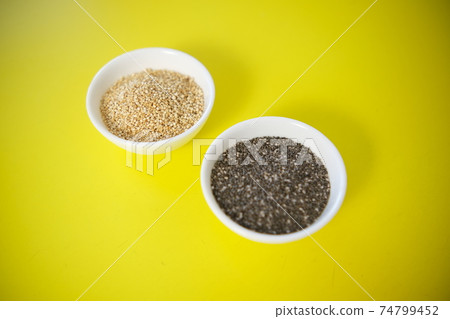 Quinoa and chia seeds are organic food for a healthy diet. In a round bowl. Two white cups. Yellow background texture 74799452