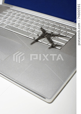 Shadow of jumbo jet over apple macintosh keyboard 74800591