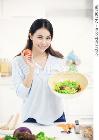 Young asian woman making food in the kitchen. Young asian woman making food in the kitchen. 74800896