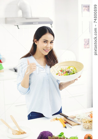 Young asian woman making food in the kitchen. Young asian woman making food in the kitchen. 74800899