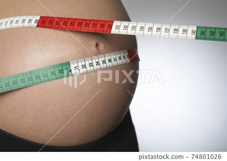 Pregnant Woman Measuring Belly With Tape Measure 74801026