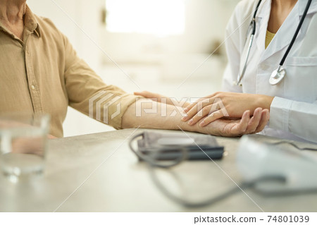 Healthcare worker rolling man sleeve up before checking blood pressure Healthcare worker rolling man sleeve up before checking blood pressure 74801039