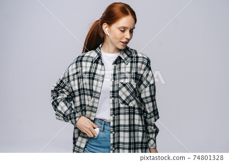 Attractive young woman wearing wireless earphones listening popular song on isolated white background Attractive young woman wearing wireless earphones listening popular song on isolated white background 74801328