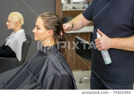 Hairdresser sprays water long hair 74801840