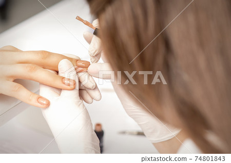Manicurist applying beige nail polish 74801843