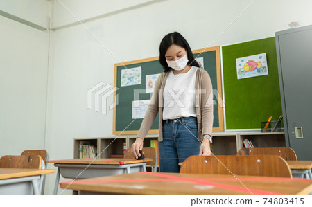 Asian woman Teacher wearing protective face mask using Tape measure on desk in classroom at school  74803415
