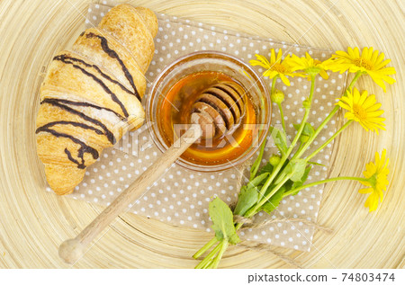 Fresh croissant, honey, yellow flowers. Fresh croissant, honey, yellow flowers. 74803474