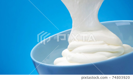Flowing fresh greek yogurt on blue background 74803920
