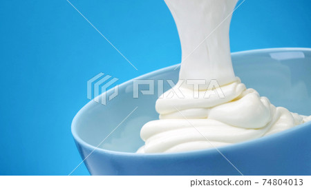 Flowing fresh greek yogurt on blue background 74804013