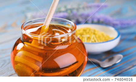 Honey in glass jar with honey dipper over wooden background 74804016