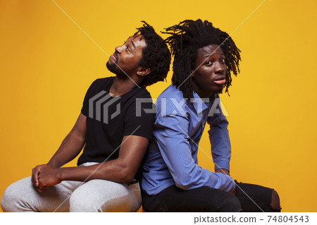 two african american guys posing cheerful together on yellow background, lifestyle people concept two african american guys posing cheerful together on yellow background, lifestyle people concept 74804543