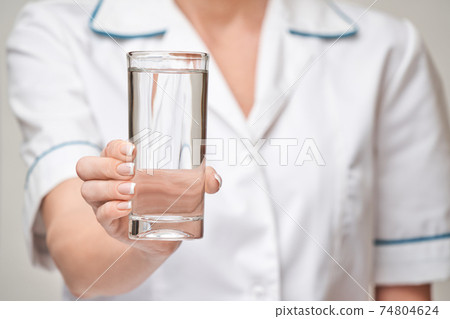 Healthy eating or lifestyle concept - female woman doctor holding and a glass of clear fresh water Healthy eating or lifestyle concept - female woman doctor holding and a glass of clear fresh water 74804624
