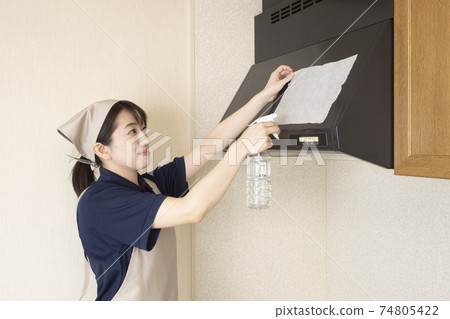 一名女清潔工將小蘇打紙片鋪在抽油煙機上。 一名女清潔工將小蘇打紙片鋪在抽油煙機上。 74805422