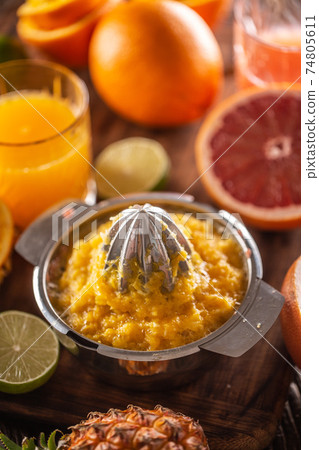 Squeezed orange pulp in a juicer with cfreshly cut citruses and a glass of juice 74805611