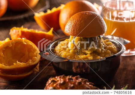 Freshly squeezed orange in a manual juicer with pulp, juice and orange skins leftovers 74805616
