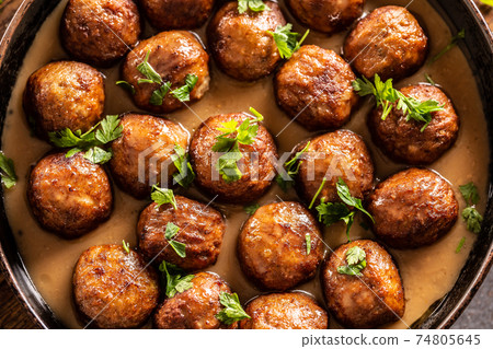 Top view of a pan with freshly-made kottbullar meatballs in a sauce Top view of a pan with freshly-made kottbullar meatballs in a sauce 74805645