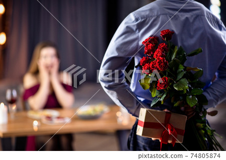 Romantic Black Guy Holding Flowers And Gift Behind Back, Surprising His Girlfriend Romantic Black Guy Holding Flowers And Gift Behind Back, Surprising His Girlfriend 74805874