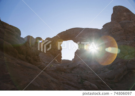 USA, sun shining through rock formation in desert USA, sun shining through rock formation in desert 74806097