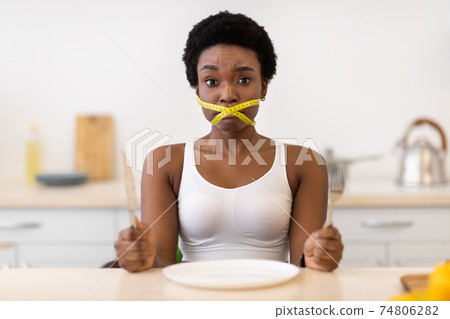 Lady Having Tied Mouth With Measuring Tape Sitting In Kitchen Lady Having Tied Mouth With Measuring Tape Sitting In Kitchen 74806282
