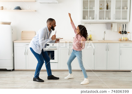 Black father and daughter dancing in the kitchen together 74806399