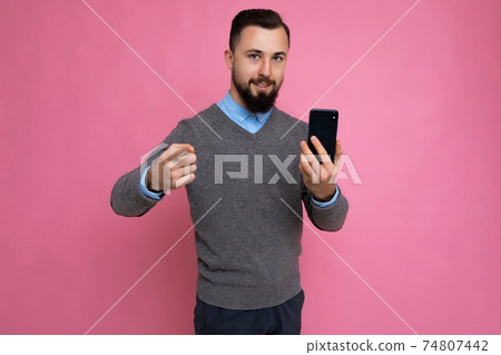 Good looking happy cool young brunette unshaven man with beardwearing stylish grey sweater and blue 74807442
