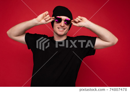 Photo shot of handsome positive smiling young man wearing black t-shirt for mockup black hat and 74807478