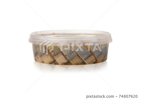 Marinated fish in a plastic container. Pieces of pickled herring in the package from the store on a white background. 74807620