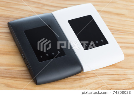 Two portable routers on the table. 4g routers on a wooden surface. Two portable routers on the table. 4g routers on a wooden surface. 74808028