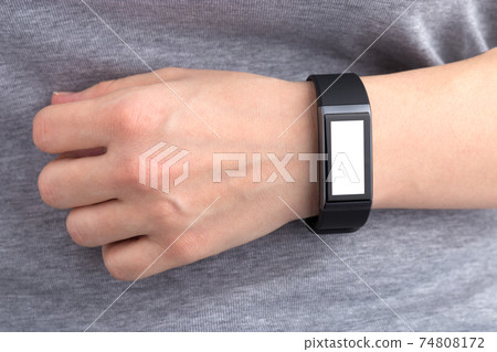 Fitness bracelet on a female hand. The hand is located on the stomach in close-up. Blank display. 74808172