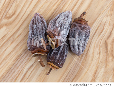 Dried persimmon on a white background. Fruits dried persimmon on a wooden surface. 74808363