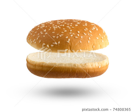Burger bun on a white background. Two halves of a burger bun flying over a white background. 74808365