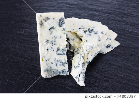 Cheese with mold on a board of stone. Gorgonzola cheese close-up on a surface of slate. 74808387